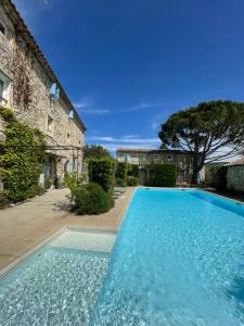 une grande piscine bleue à côté d'un bâtiment dans l'établissement Domaine Les Mejeonnes, à Valaurie