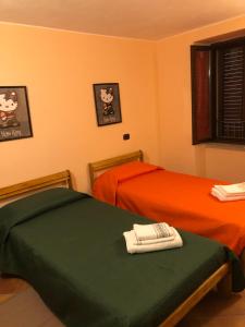 two twin beds in a room with orange at Basicò un balcone sul mare - Casa SALITA FOTI -Case vacanza Sicilia&Toscana- in Basicò