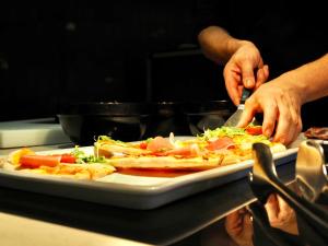 a person cutting up a pizza on a plate at BQ Belvedere Hotel in Palma de Mallorca