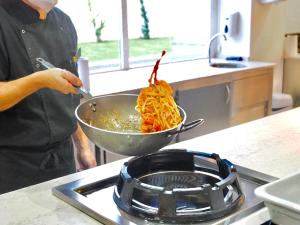 a person cooking food in a bowl on a stove at BQ Belvedere Hotel in Palma de Mallorca