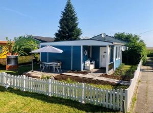 a blue house with a white fence and an umbrella at Sonniges Ferienhaus Fischer-Huus vor Usedom & direkt am Haff und Wasserzugang in Mönkebude