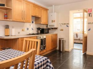a kitchen with wooden cabinets and a table with a table cloth at Harbour View in Buckie
