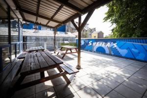 um pátio com duas mesas de piquenique numa varanda em Sheilas Tourist Hostel em Cork