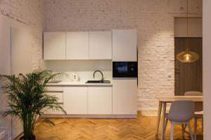 a kitchen with white cabinets and a table at Sympatyczne studio z palmą areka / A nice studio with areka palm tree in Łódź