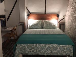 sypialnia z łóżkiem z zieloną kołdrą w obiekcie HERVÀS Y VUELVES ( la casita de la piedra ) w mieście Hervás