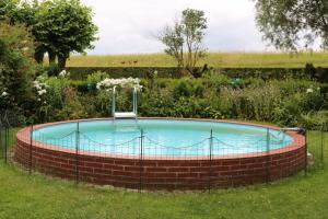 a circular pool in a garden with a brick wall at Ferienwohnung mit Sauna in Bleckede