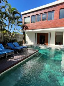 a swimming pool with chairs and a house at Villa Sassy in Seminyak