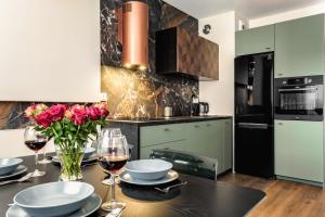 a kitchen with a table with glasses of wine and roses at Aparthotel Plac Litewski Premium in Lublin