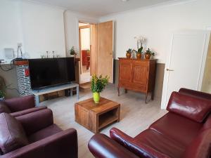 a living room with two couches and a flat screen tv at Haspengouws Hoeveke in Borgloon
