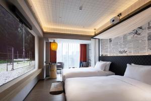 a hotel room with two beds and a window at Arthur Hotel Canton Tower Guangzhou-广州塔骑士物语酒店 in Guangzhou