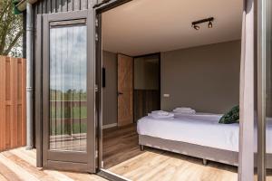 Schlafzimmer mit einem Bett und einer Glasschiebetür in der Unterkunft Erfgoedpark De Hoop Appartementen in Uitgeest