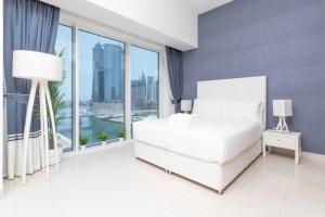 a bedroom with a white bed and a large window at Cozy Studio at Dubai Water Canal next to Downtown in Dubai
