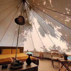 Under Canvas Bornholm في Østermarie: غرفة مع خيمة مع سرير وطاولة
