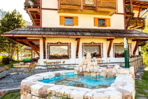 a house with a fountain in front of a building at Hotel Salvan in Campitello di Fassa