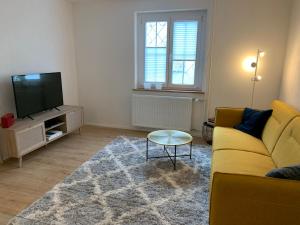 ein Wohnzimmer mit einem gelben Sofa und einem TV in der Unterkunft Ferienwohnungen Bohner/ Wohnung Katharina in Meersburg