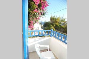 a white chair sitting on a balcony with flowers at 3 min from the beach-White&blue house in Apollon in Apollon