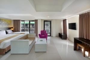 a hotel room with a large bed and a pink chair at Rofa Kuta Hotel - CHSE Certified in Legian