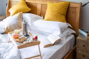 Una cama con una mesa con una bandeja de comida. en The Bell at Sapperton en Cirencester
