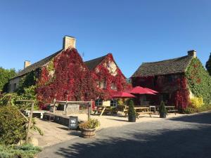 a building covered in ivy with tables and chairs at The Bell at Sapperton in Cirencester