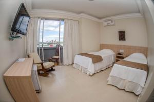 a hotel room with two beds and a window at Hotel Desbravador in Chapecó