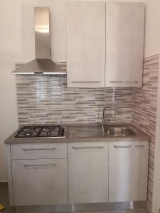eine Küche mit weißen Schränken und einem Waschbecken in der Unterkunft House Pierclaudio e Domitilla in Monte San Biagio