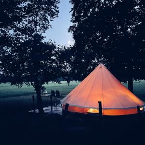 a tent sitting in the grass under a tree at Under Canvas Bornholm in Østermarie