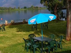 einen Tisch und Stühle mit einem blauen Regenschirm und einem See in der Unterkunft House Pierclaudio e Domitilla in Monte San Biagio
