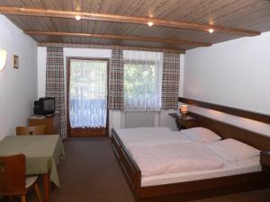 a bedroom with a bed and a table and two windows at Gasthof - Pension zur Post in Achslach