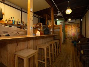 un bar con una fila de taburetes en un restaurante en Himeji 588 Guest House en Himeji