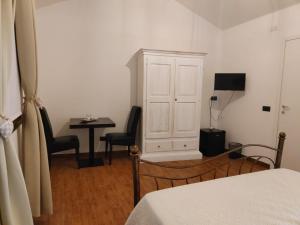 a bedroom with a white cabinet and a table and chairs at Casa Janas Affittacamere Bed & Breakfast in Piscinas