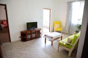 a living room with a tv and a couch and chairs at Casa Mama in Quatre Bornes