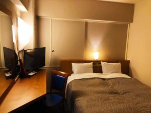 a bedroom with a bed and a flat screen tv at Hotel Ace Morioka in Morioka