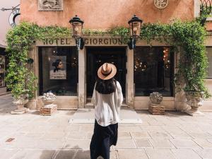 Una donna con un cappello davanti a un negozio di Hotel Giorgione a Venezia