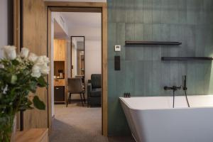 a bathroom with a bath tub and a vase of flowers at Hotel Alexander in Krakow