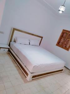 - une chambre avec un grand lit et une tête de lit en bois dans l'établissement Al Kasbah, à El Jadida