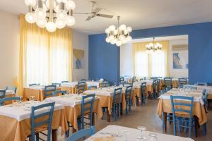 ein Esszimmer mit weißen Tischen und blauen Wänden in der Unterkunft Hotel San Francisco in Lido di Savio