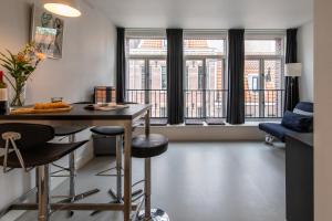 een woonkamer met een tafel, stoelen en ramen bij Tweede Laurierdwarsstraat Apartment in Amsterdam
