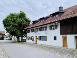 a white building with a red roof on a street at Pension Hirsch in Seeg