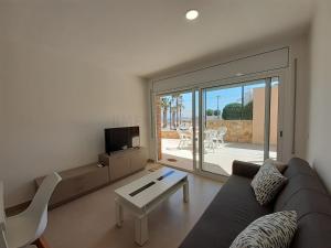 uma sala de estar com um sofá, uma mesa e uma televisão em Apartamentos Dins Mar Apto. 3 em Torredembarra