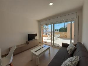 a living room with a couch and a table and a tv at Apartamentos Dins Mar Apto. 3 in Torredembarra