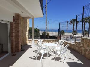 un patio con mesa, sillas y el océano en Apartamentos Dins Mar Apto. 3, en Torredembarra