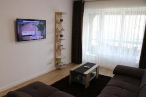 uma sala de estar com um sofá e uma televisão na parede em CityApart GranVia Marina - Cazare în Constanța, lângă stațiunea Mamaia em Constança