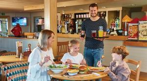 un homme avec deux enfants assis à une table dans un restaurant dans l'établissement Luxury Static Home 2 Bed Sleeps 6, à Great Yarmouth