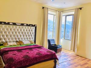 a bedroom with a bed and a chair and windows at Hunza Hidden Palace in Alīābād