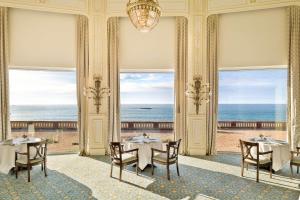 
a dining room table with chairs and a balcony at Hôtel du Palais Biarritz, in The Unbound Collection by Hyatt in Biarritz
