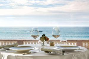 a table with two wine glasses and a view of the ocean at Hôtel du Palais Biarritz, in The Unbound Collection by Hyatt in Biarritz