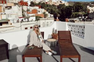 a woman sitting on a bench on a roof at Villa Nestor in Ingenio