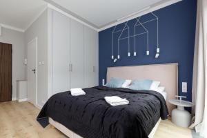 a bedroom with a blue accent wall and a bed at Apartments Warsaw Pawia by Renters in Warsaw