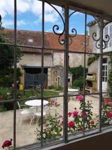 ein Fenster mit Gartenblick, einem Tisch und Stühlen in der Unterkunft Le Relais des Roses- Chambres d'hôtes in Vatan