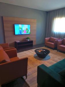 a living room with a television on a wall at Hotelog in Campina Grande do Sul